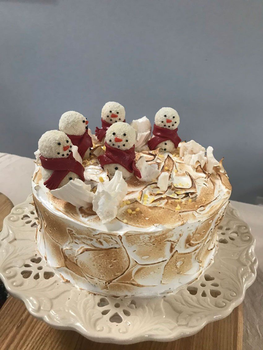 Christmas cake with snowmen wearing red scarfs sat on the top
