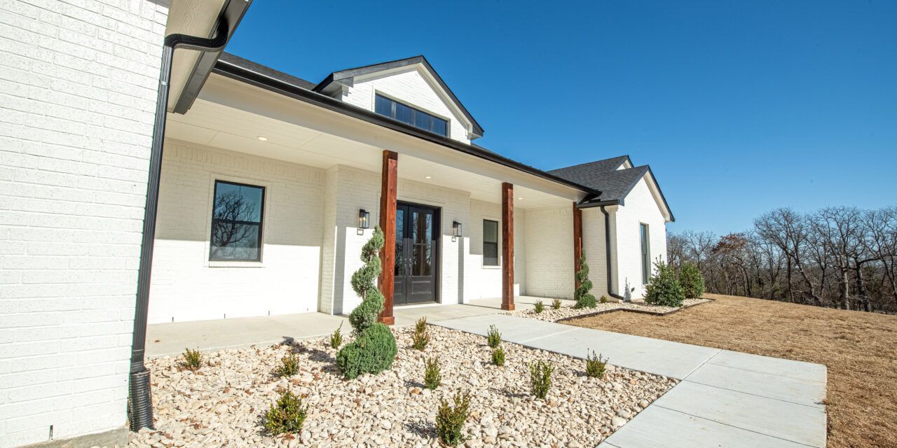 A large white house with a porch and a walkway leading to it.