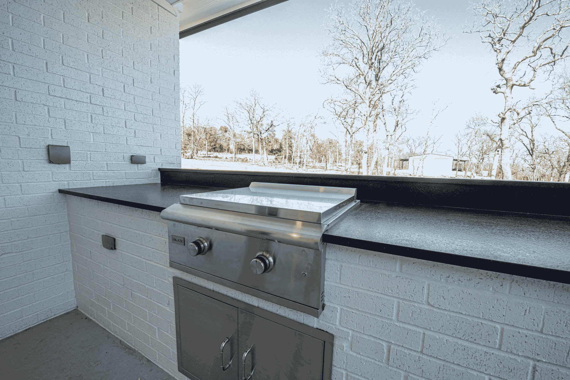A kitchen with a grill and a window with trees in the background.