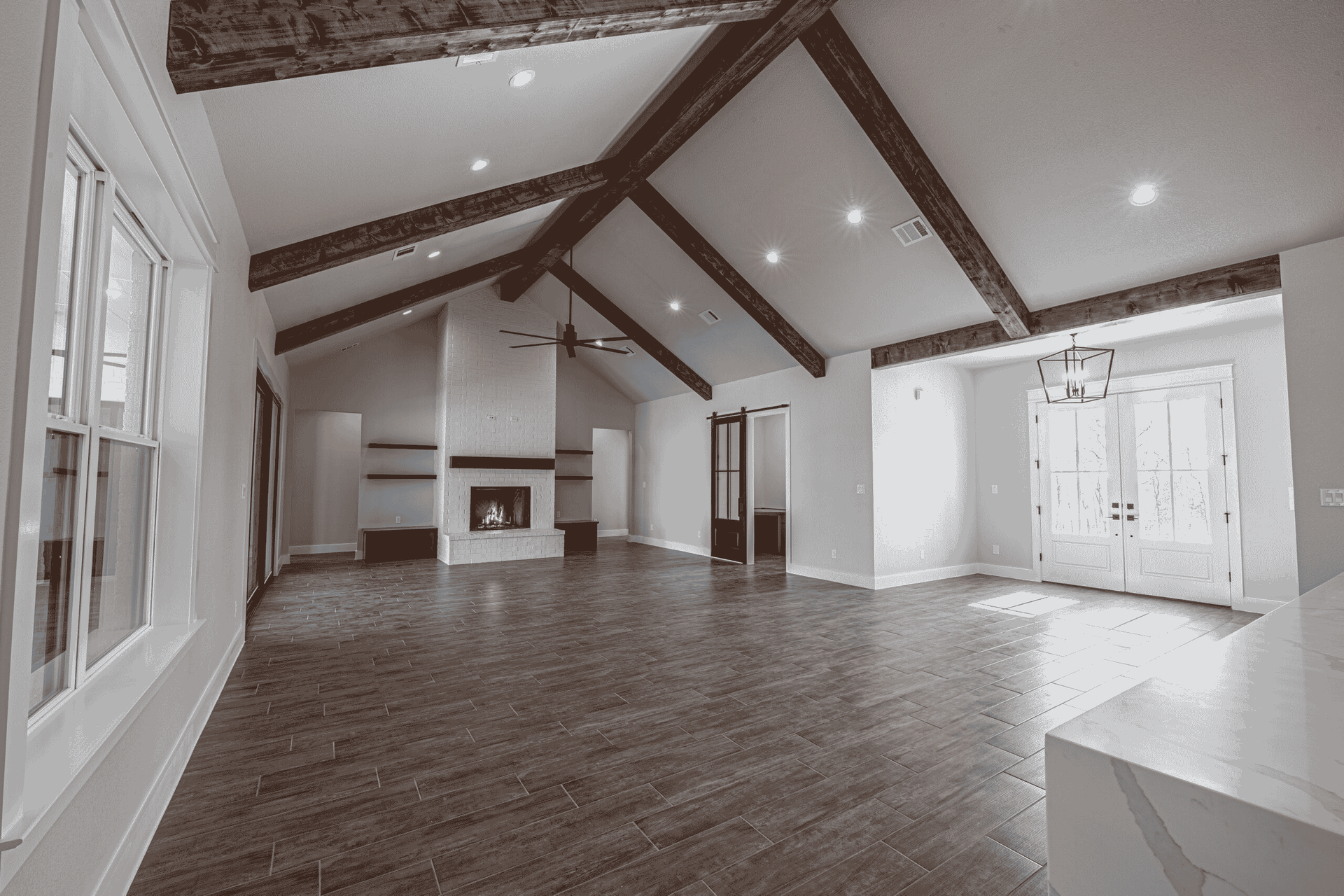 An empty living room with a vaulted ceiling and wooden beams.