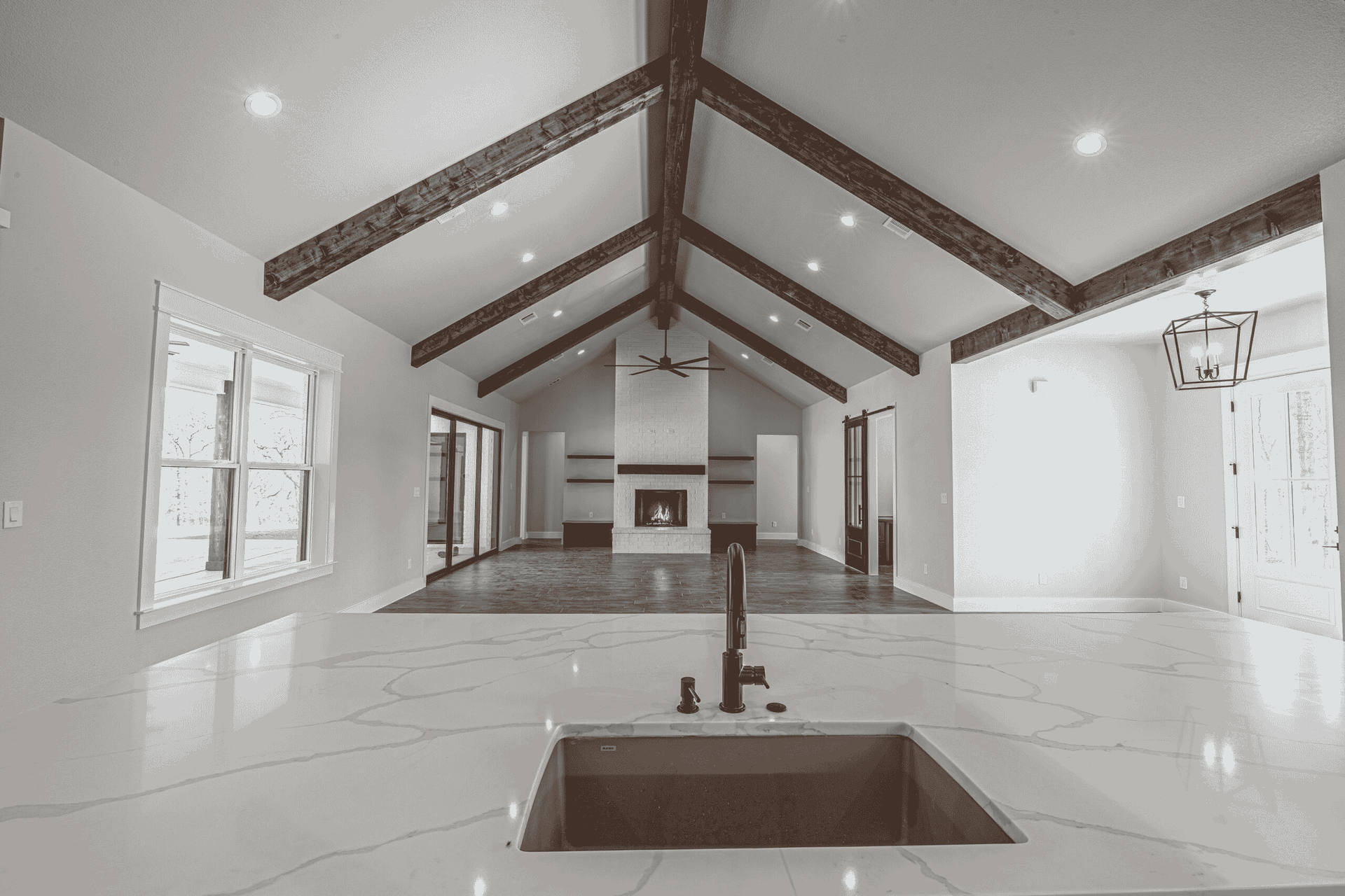 A black and white photo of a kitchen with a sink and a fireplace.