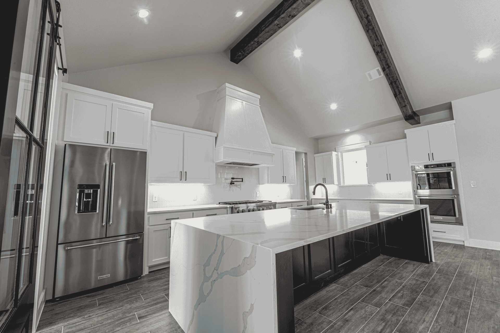 A kitchen with white cabinets , stainless steel appliances , and a large island.
