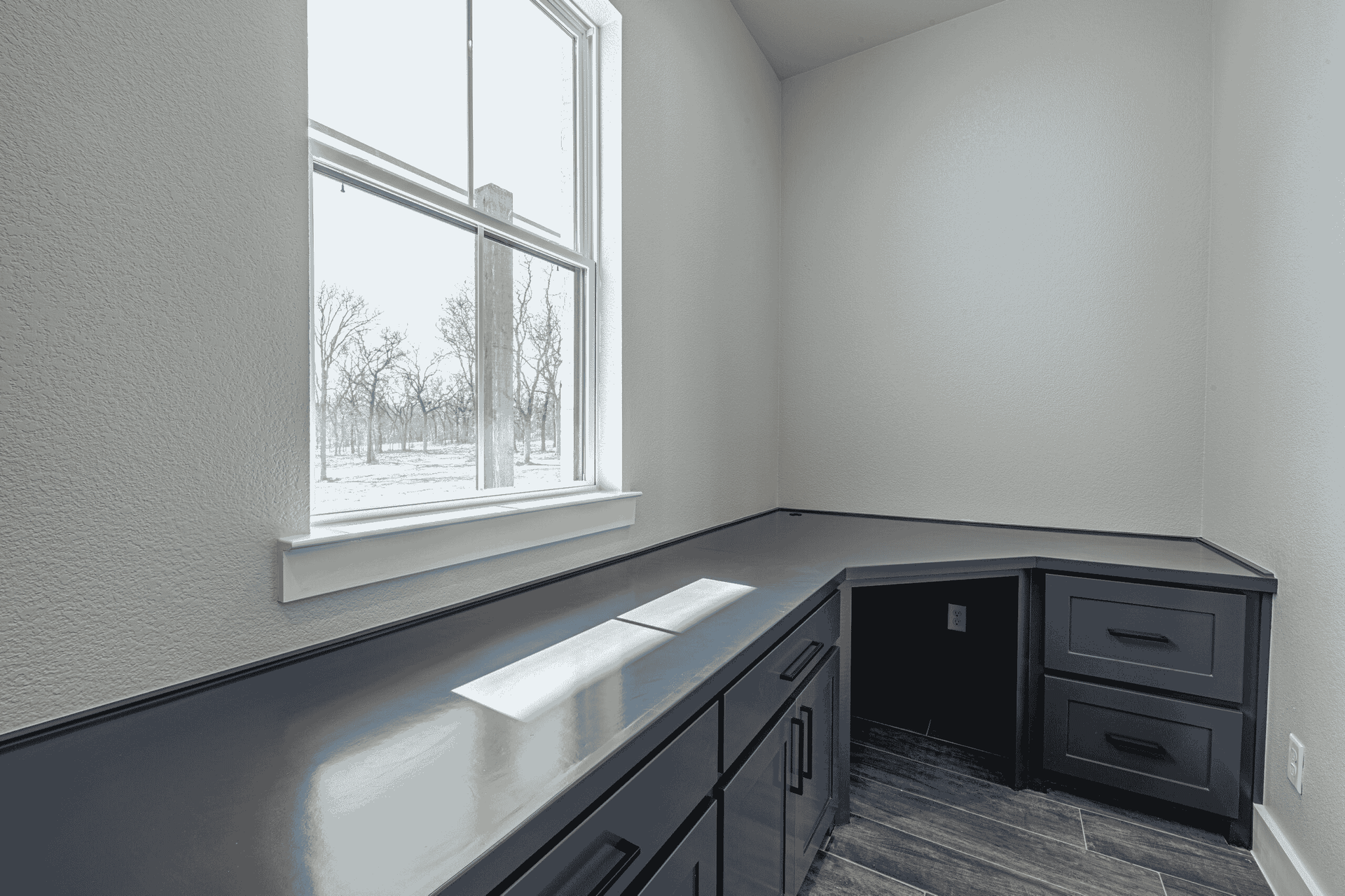 A room with a desk , drawers , and a window.