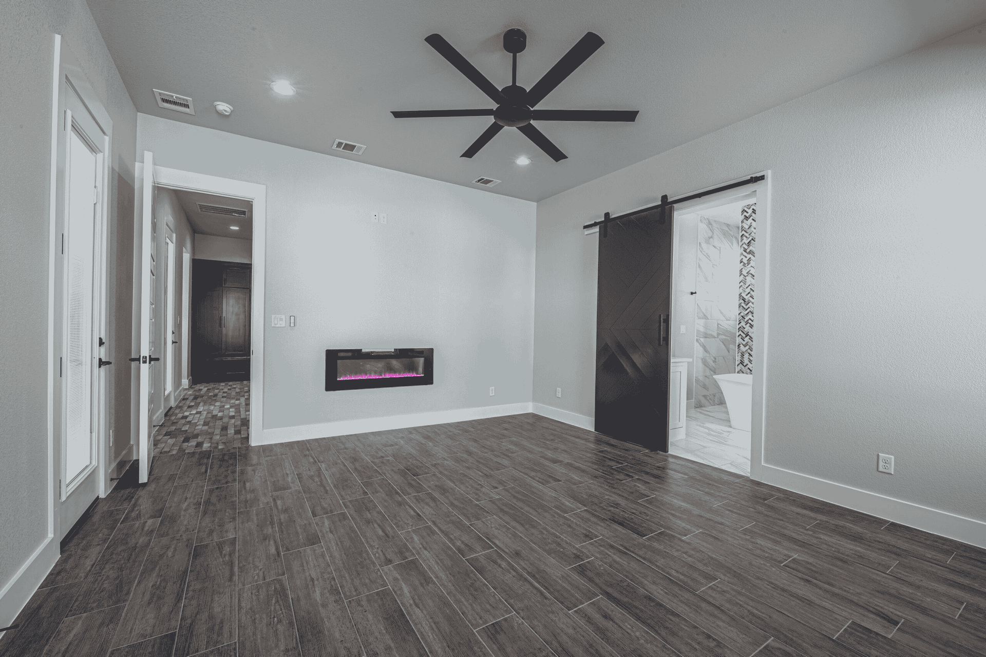An empty room with a fireplace and a ceiling fan.