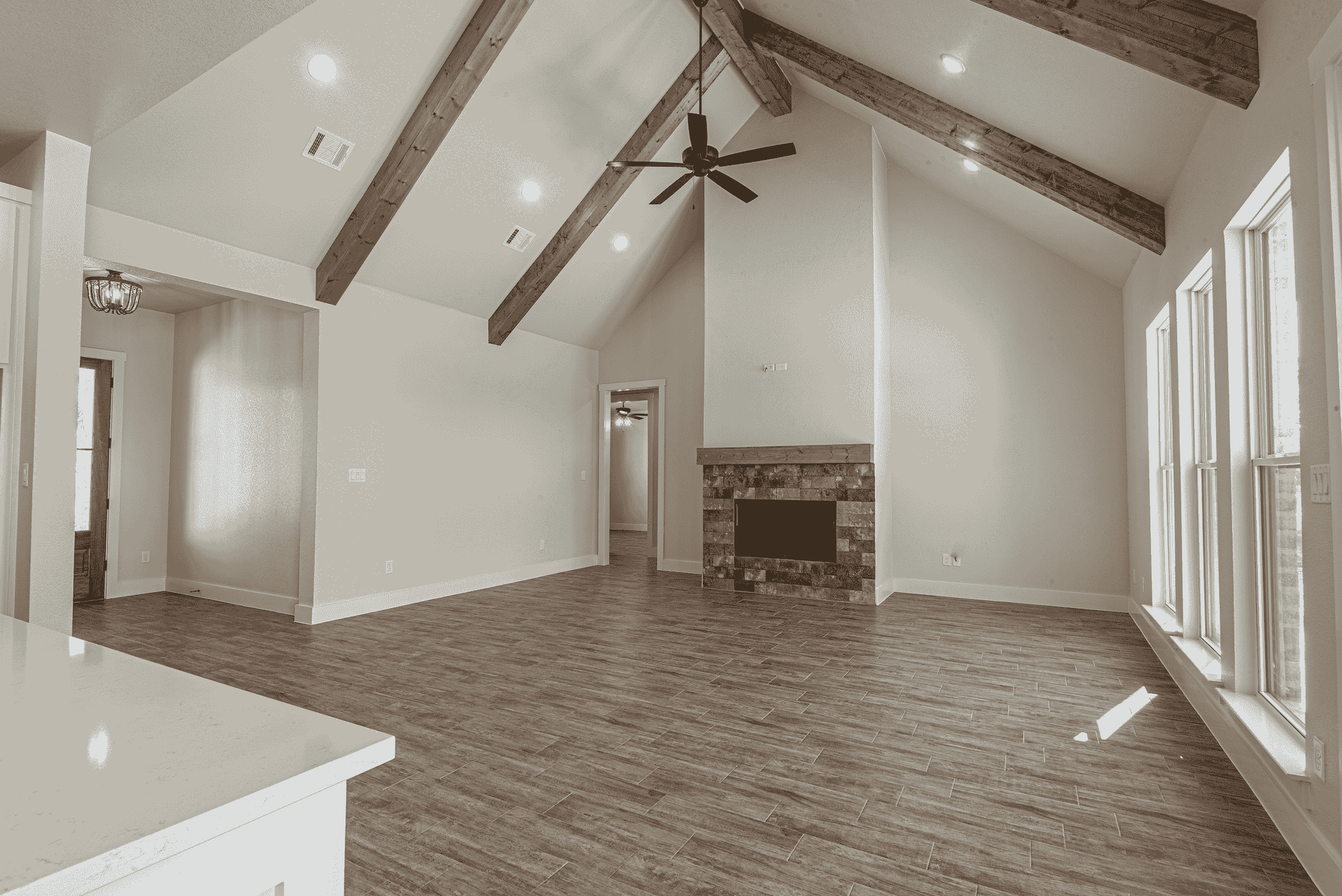 An empty living room with a fireplace and ceiling fan.