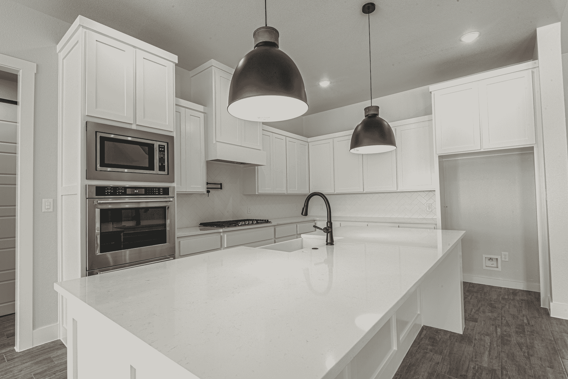 A black and white photo of a kitchen with white cabinets and a large island.