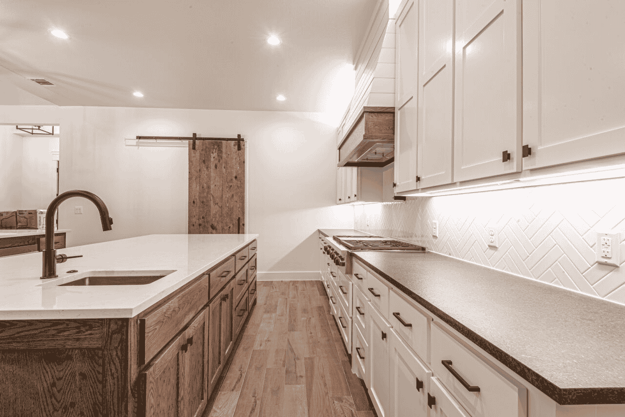 A kitchen with white cabinets and wooden floors and a sliding barn door.