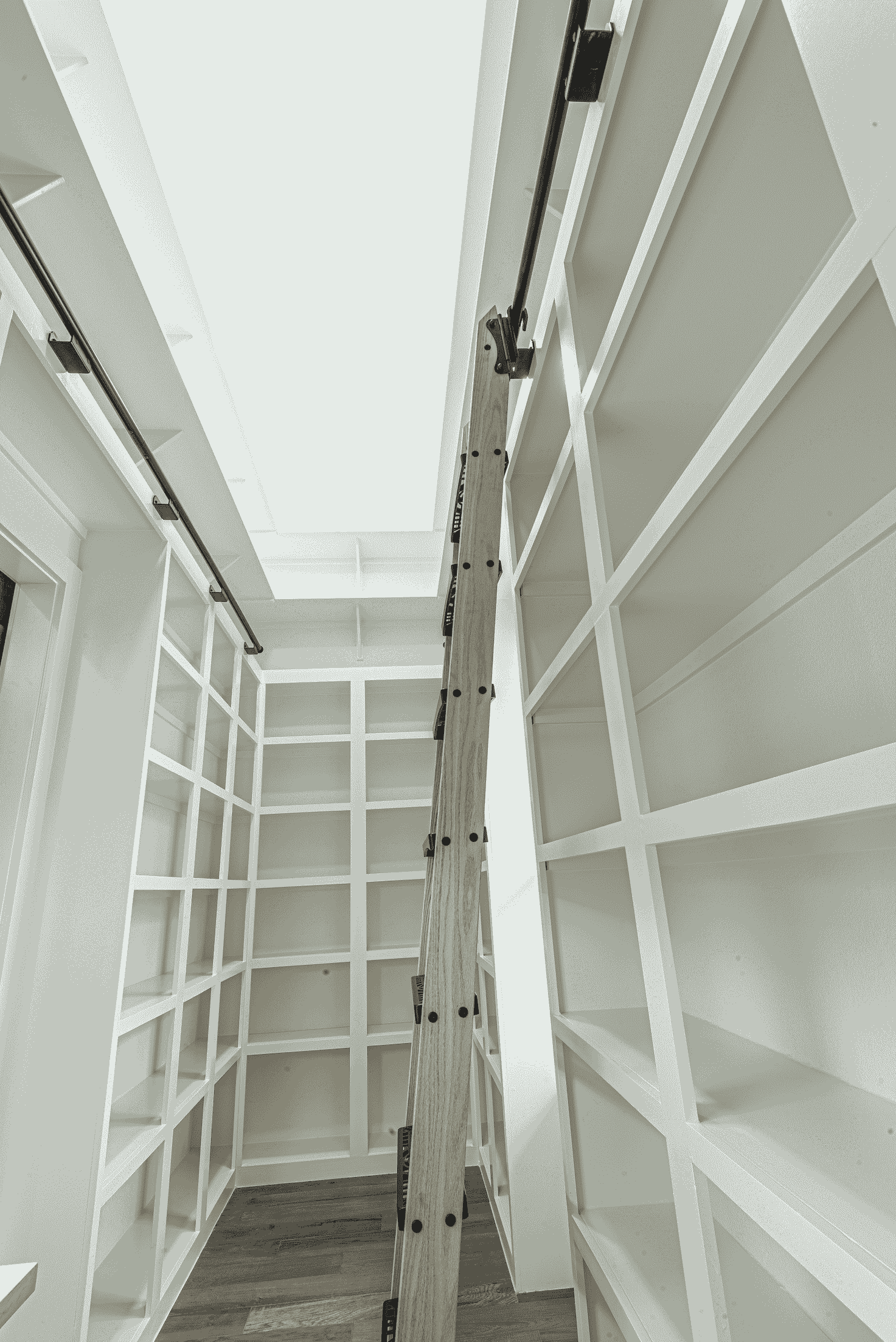 A black and white photo of a walk in closet with lots of shelves.