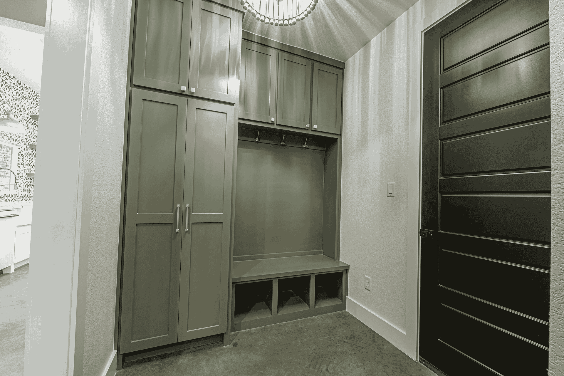 A black and white photo of a hallway with lots of cabinets and a black door.