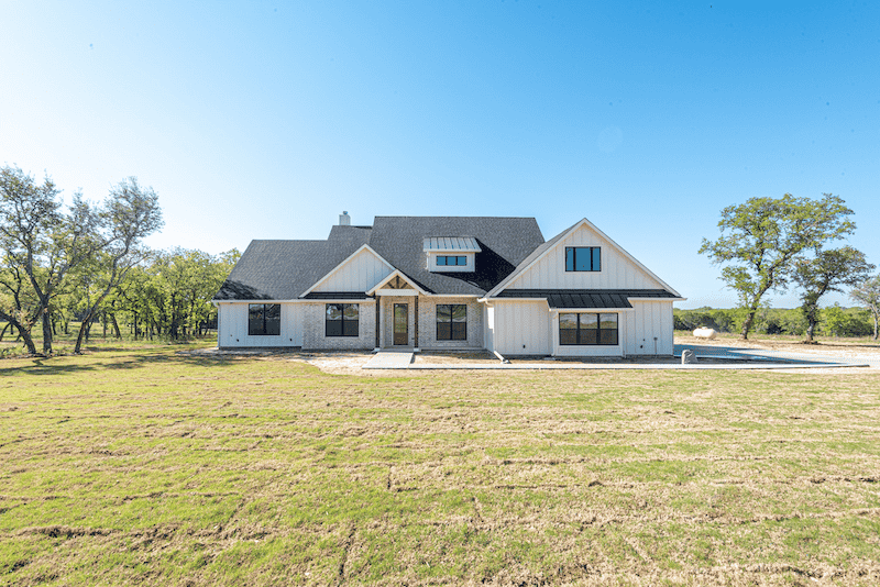 A house with a tree in front of it and a walkway leading to it.
