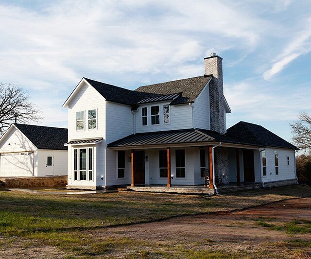 A large white house with a black roof and a porch