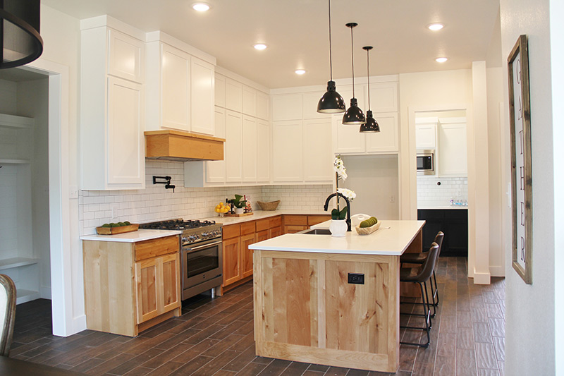 A kitchen with white cabinets and wooden cabinets and a large island in the middle.