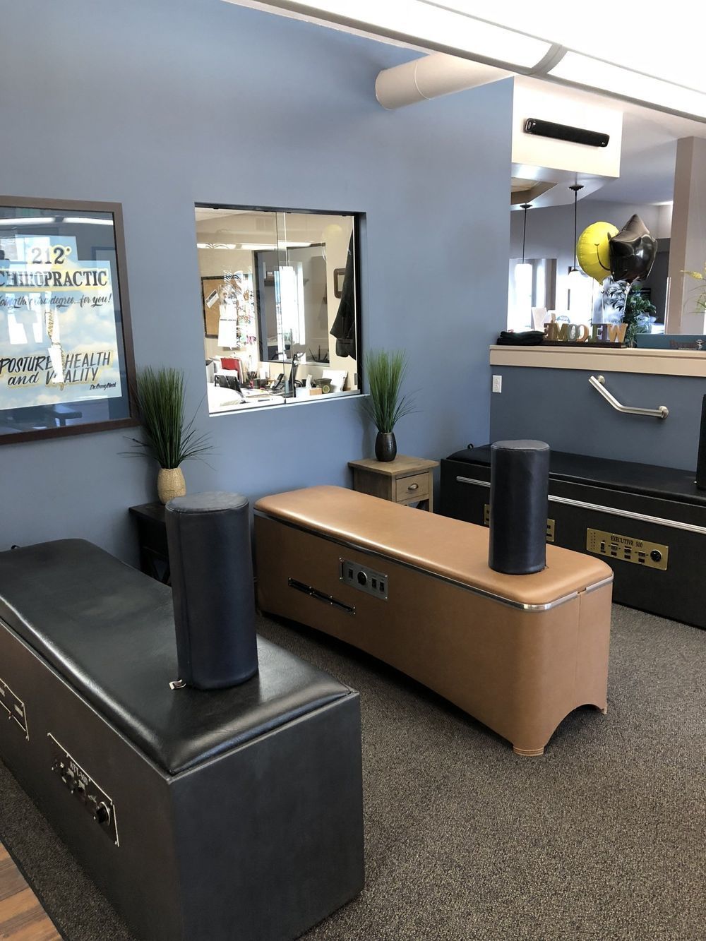 Two dark blue speakers on tan and black benches in a room with blue walls and a window.