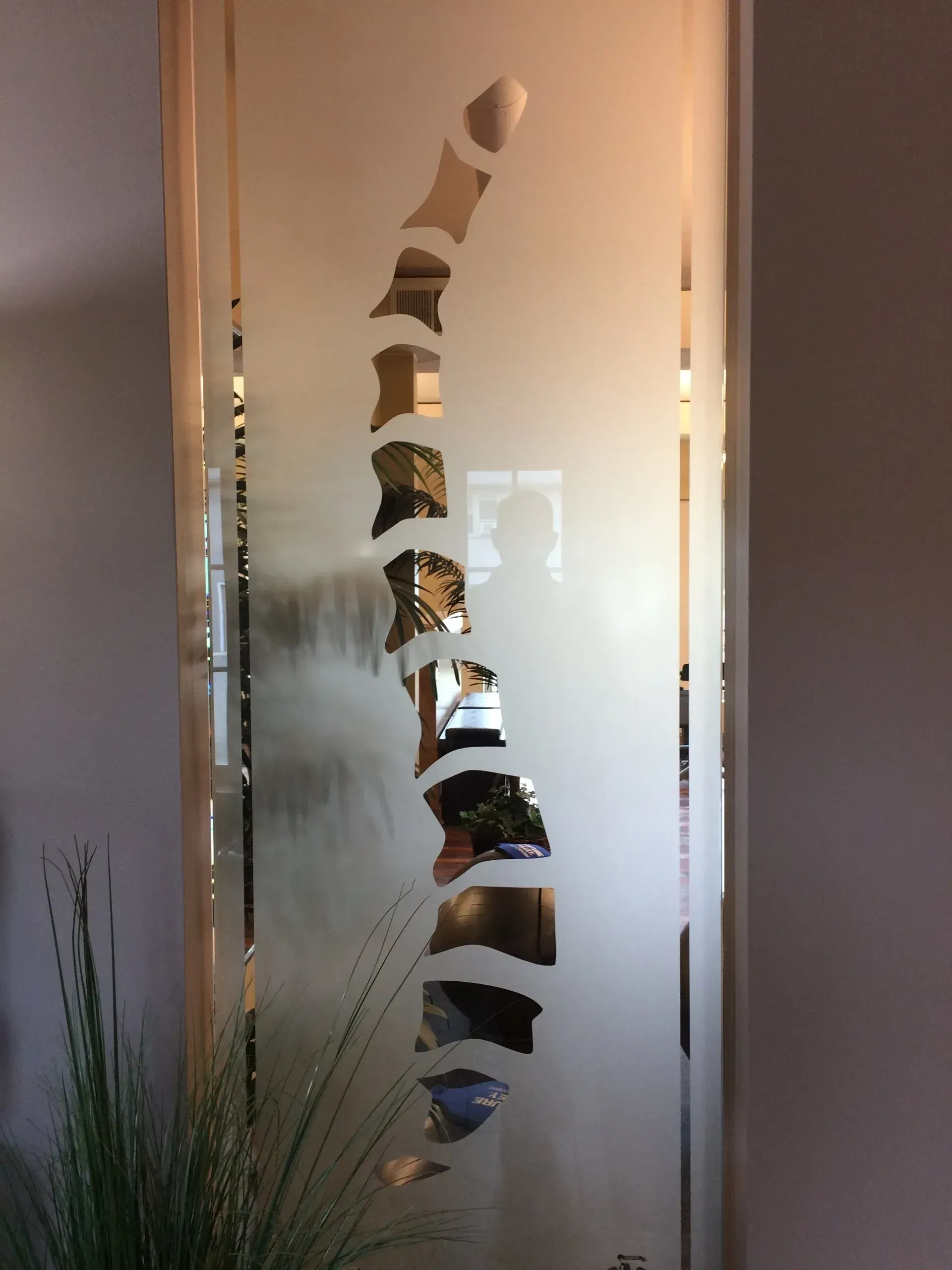 Frosted glass door with a decorative, vertical cutout revealing a glimpse of the interior.