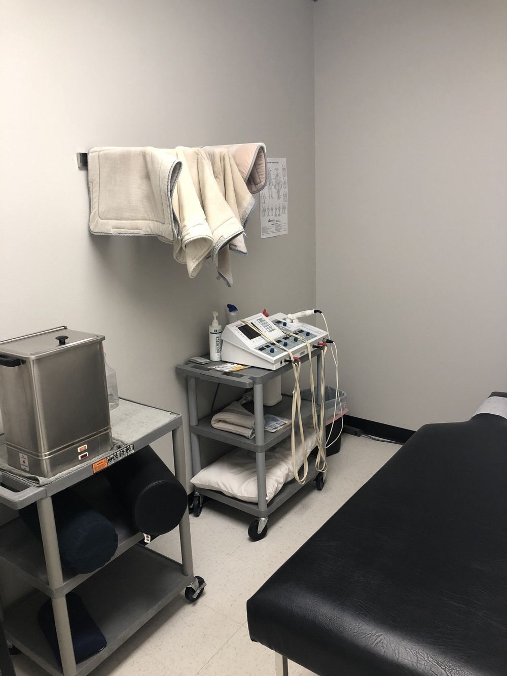 Physical therapy room: Treatment table, ultrasound machine, towels, and a heating unit.