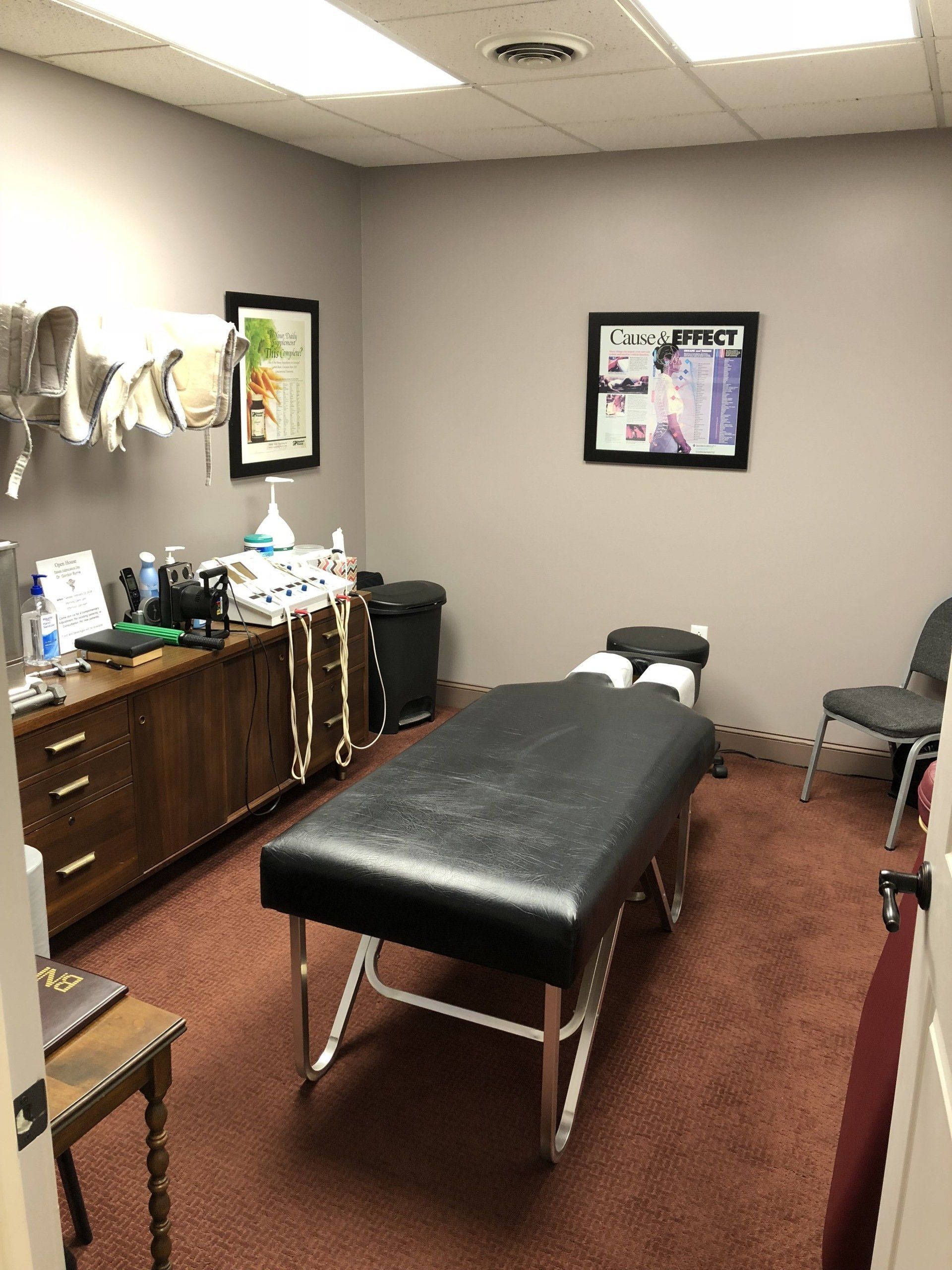 Chiropractor's office with massage table, cabinets, medical equipment, and two framed posters; 