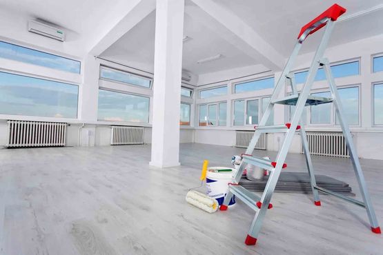 Pièce lumineuse et vide avec de grandes fenêtres et une échelle rouge au premier plan