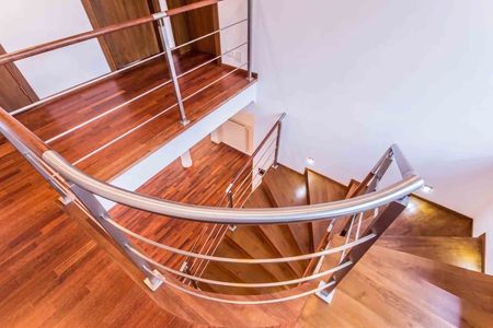 Escalier en bois courbé avec rampes en métal dans un intérieur lumineux