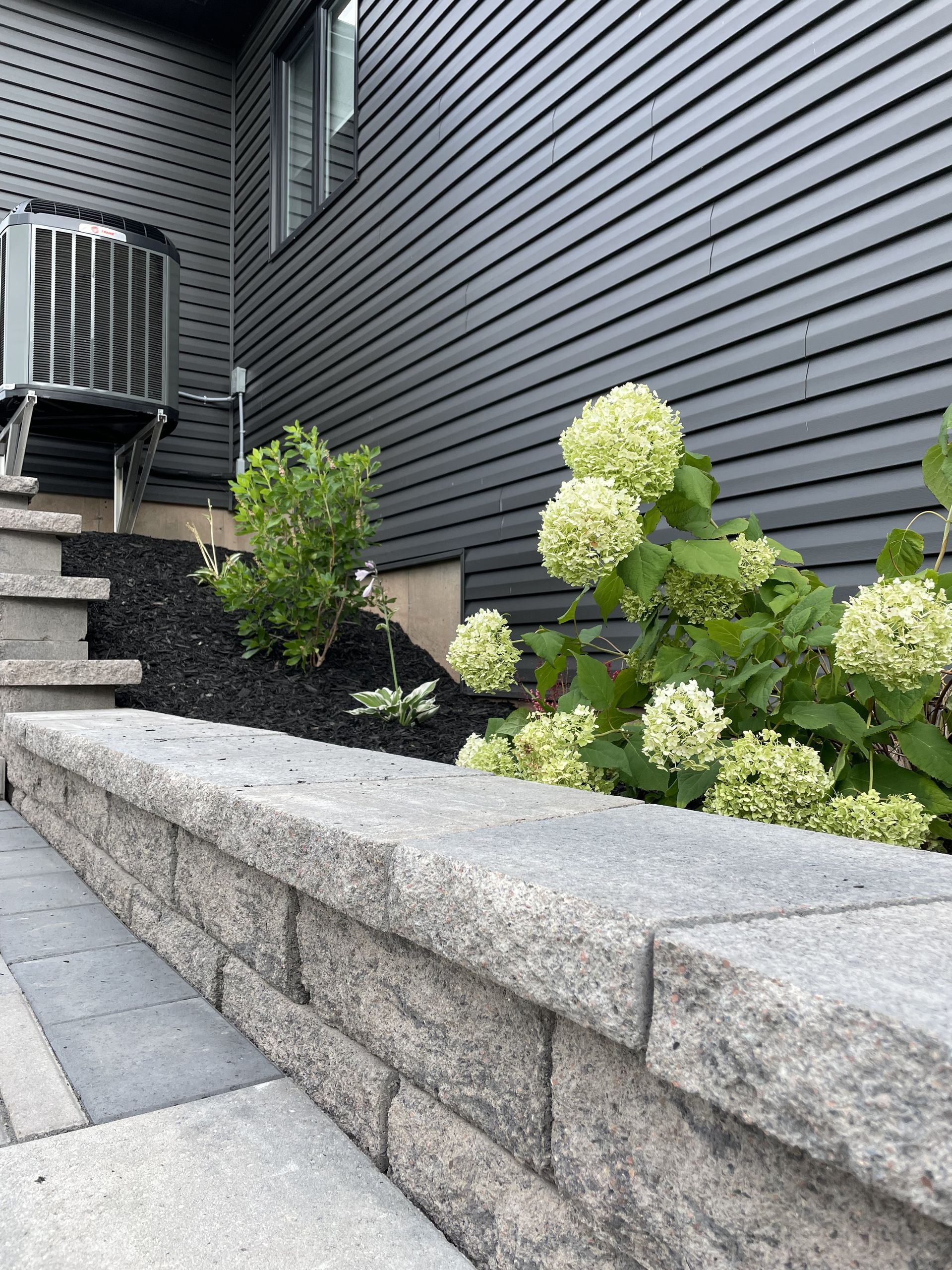A stone wall with flowers in front of a house.