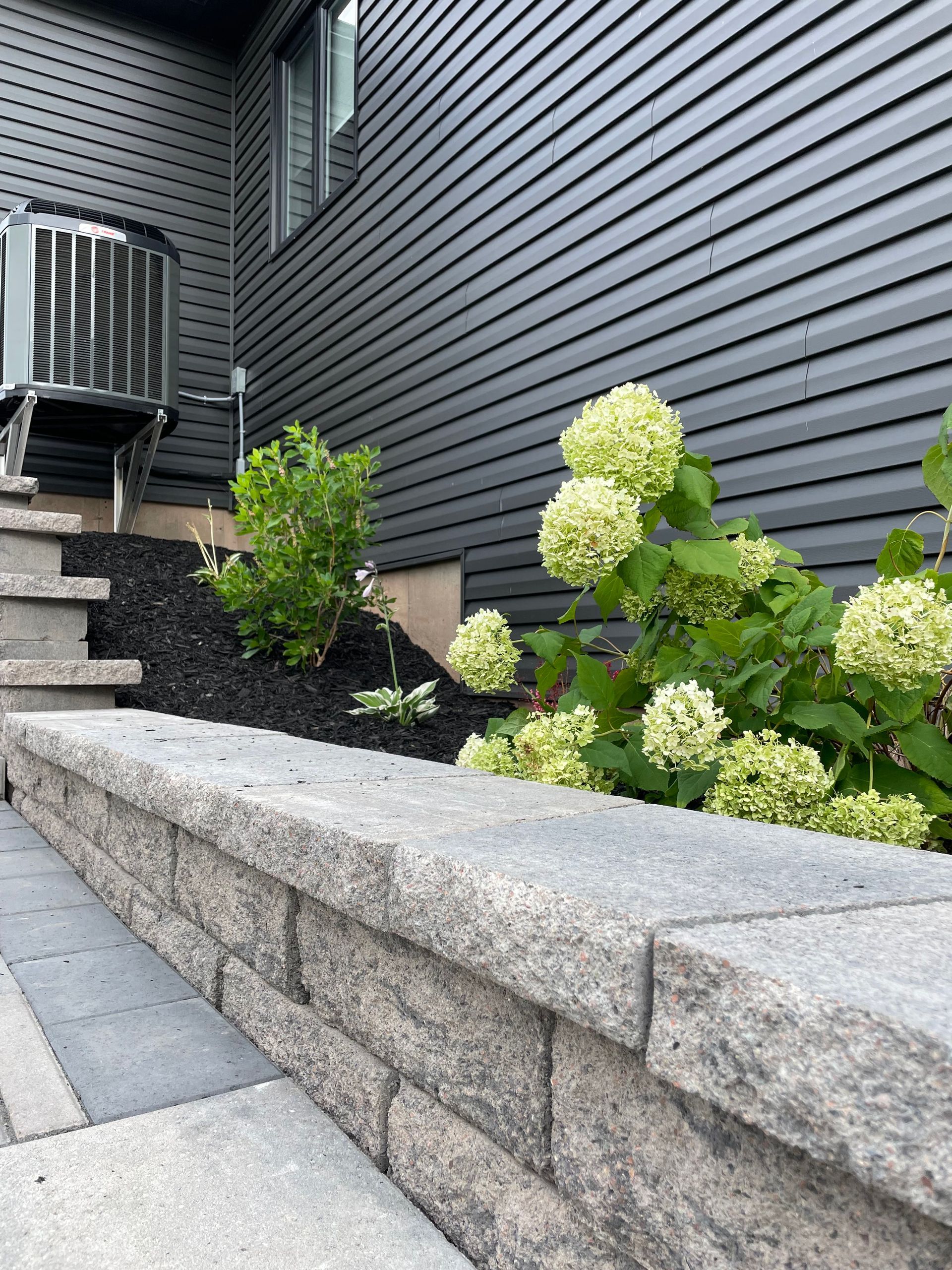 A stone wall with flowers in front of a house.