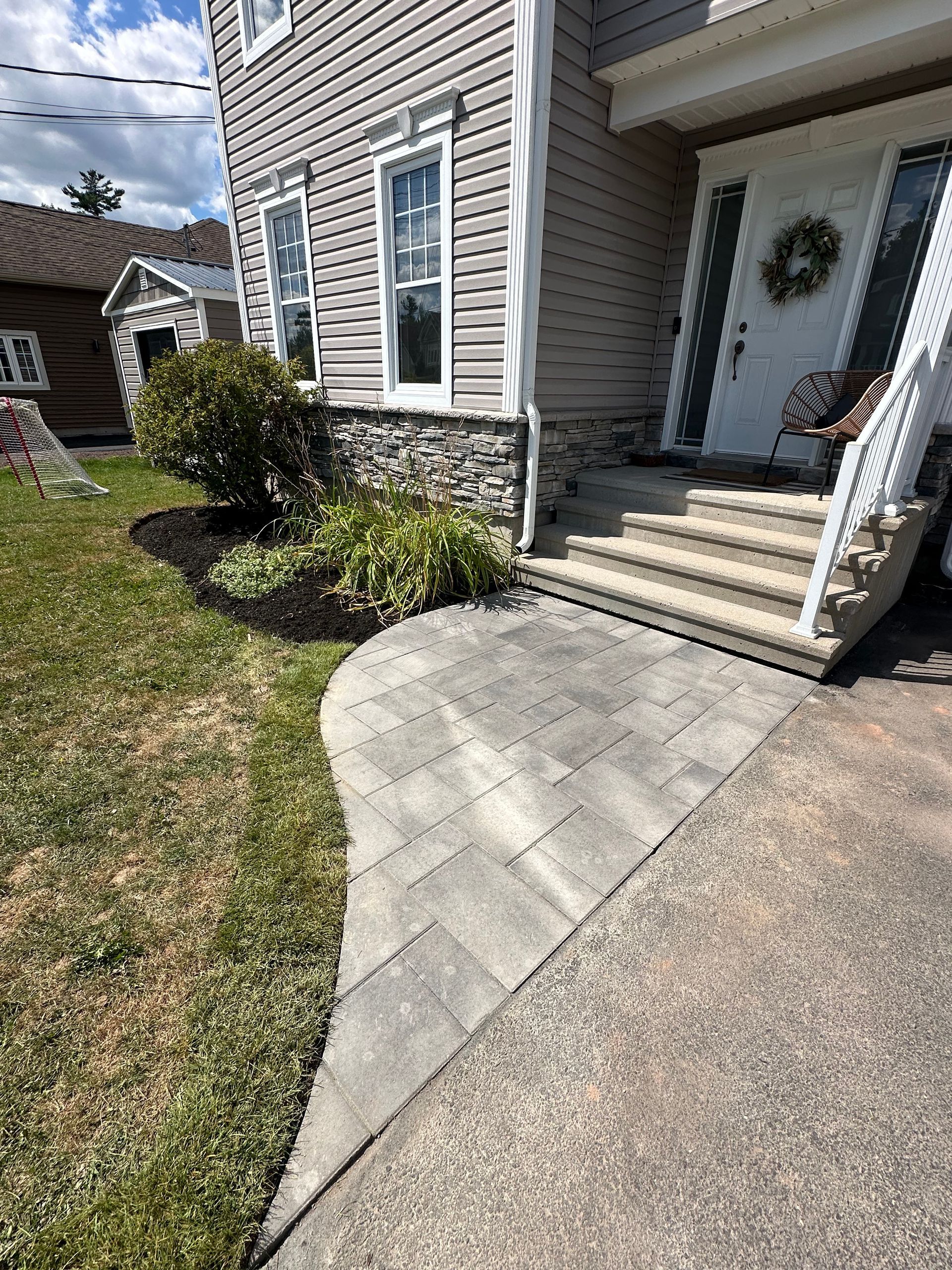 A concrete walkway leading to the front door of a house.