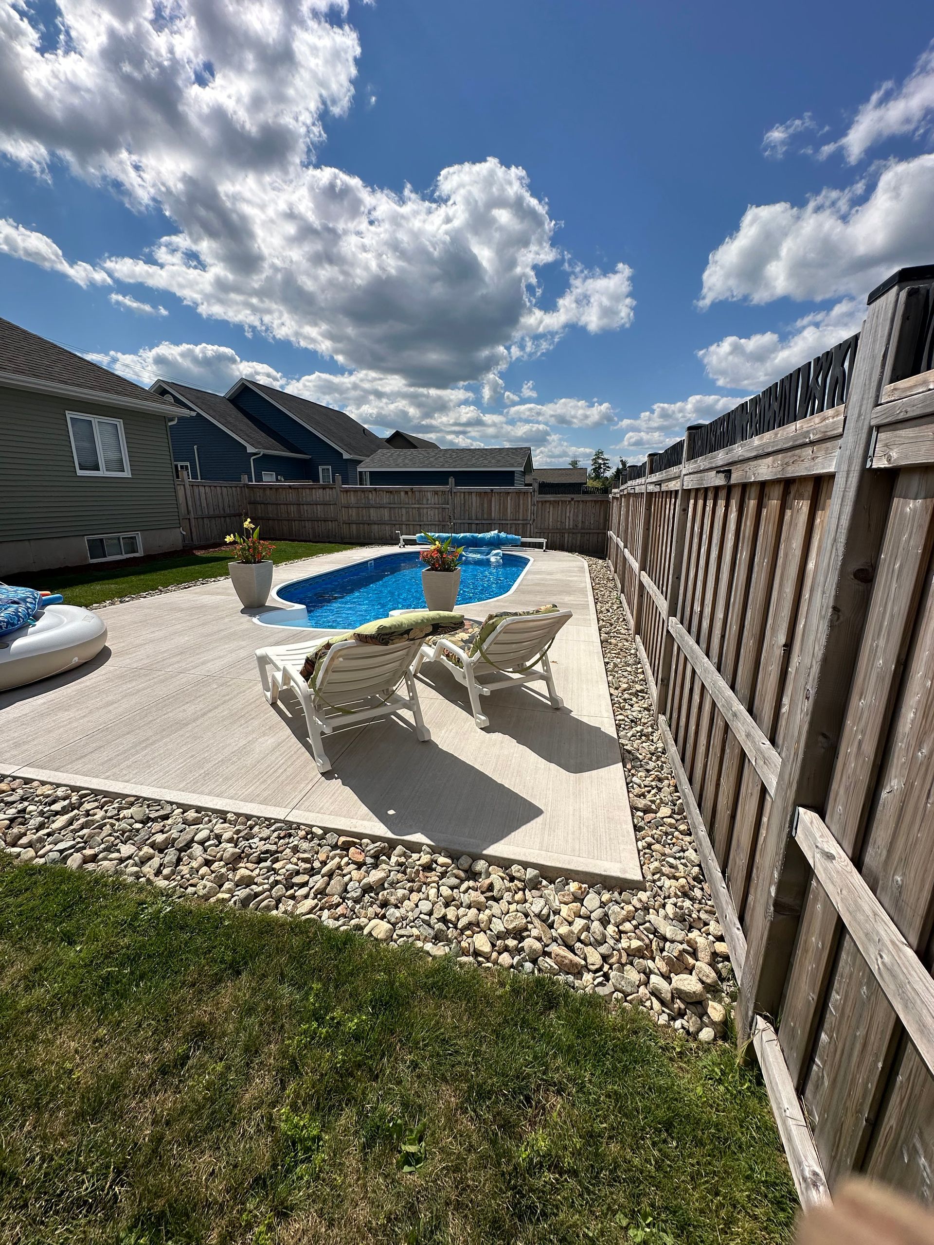 A backyard with a swimming pool and a wooden fence.