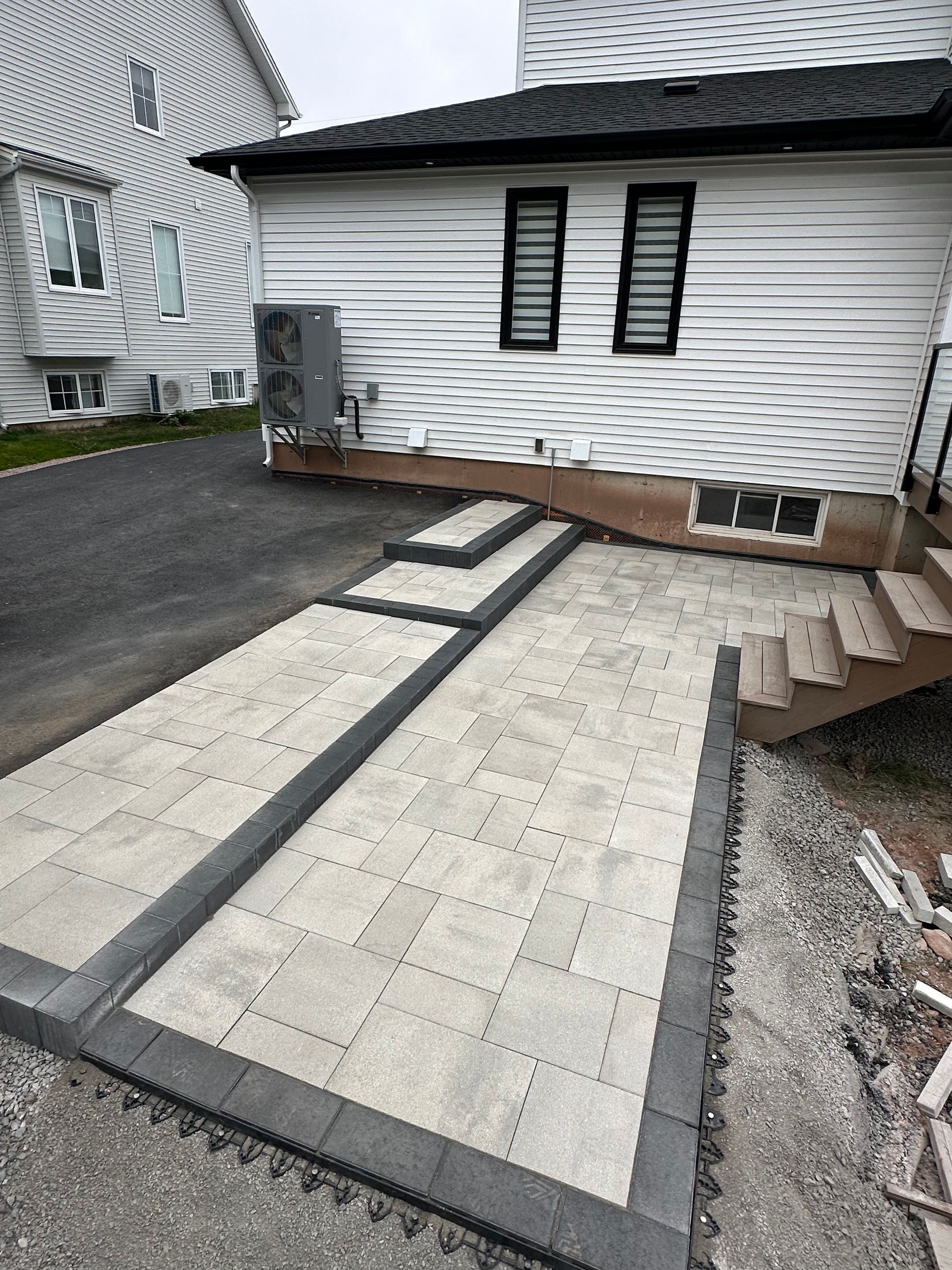 A white house with a patio and stairs in front of it.