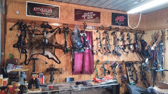 Wall with archery bows and equipment, banners, and animal hide.