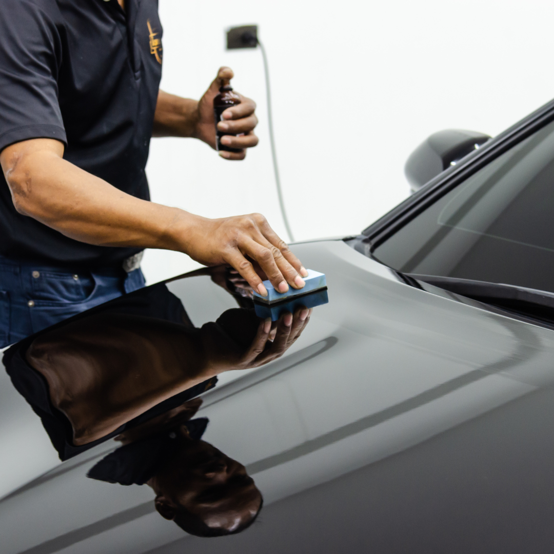 A man is polishing the hood of a black car