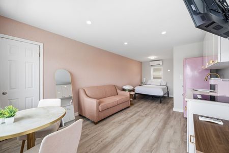 Two beds in a hotel room with peach headboards and light pink bedskirts.