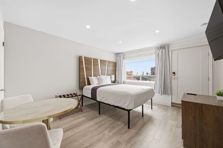 Hotel room with two double beds, peach-colored headboards and bed skirts, a window with curtains.