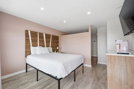 Hotel room with two double beds, peach-colored headboards and bed skirts, a window with curtains.