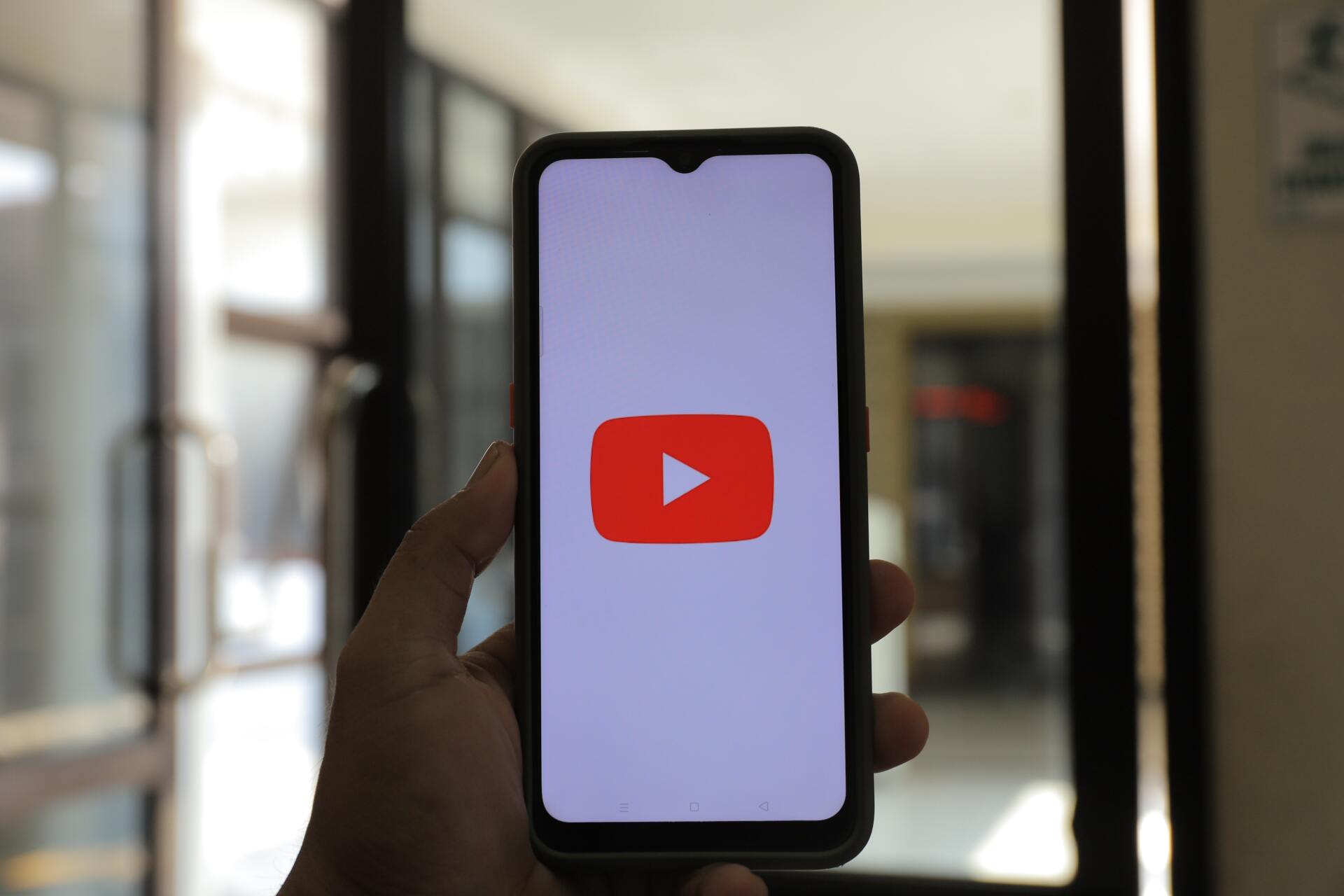 Close up hand holding phone with youtube logo on it