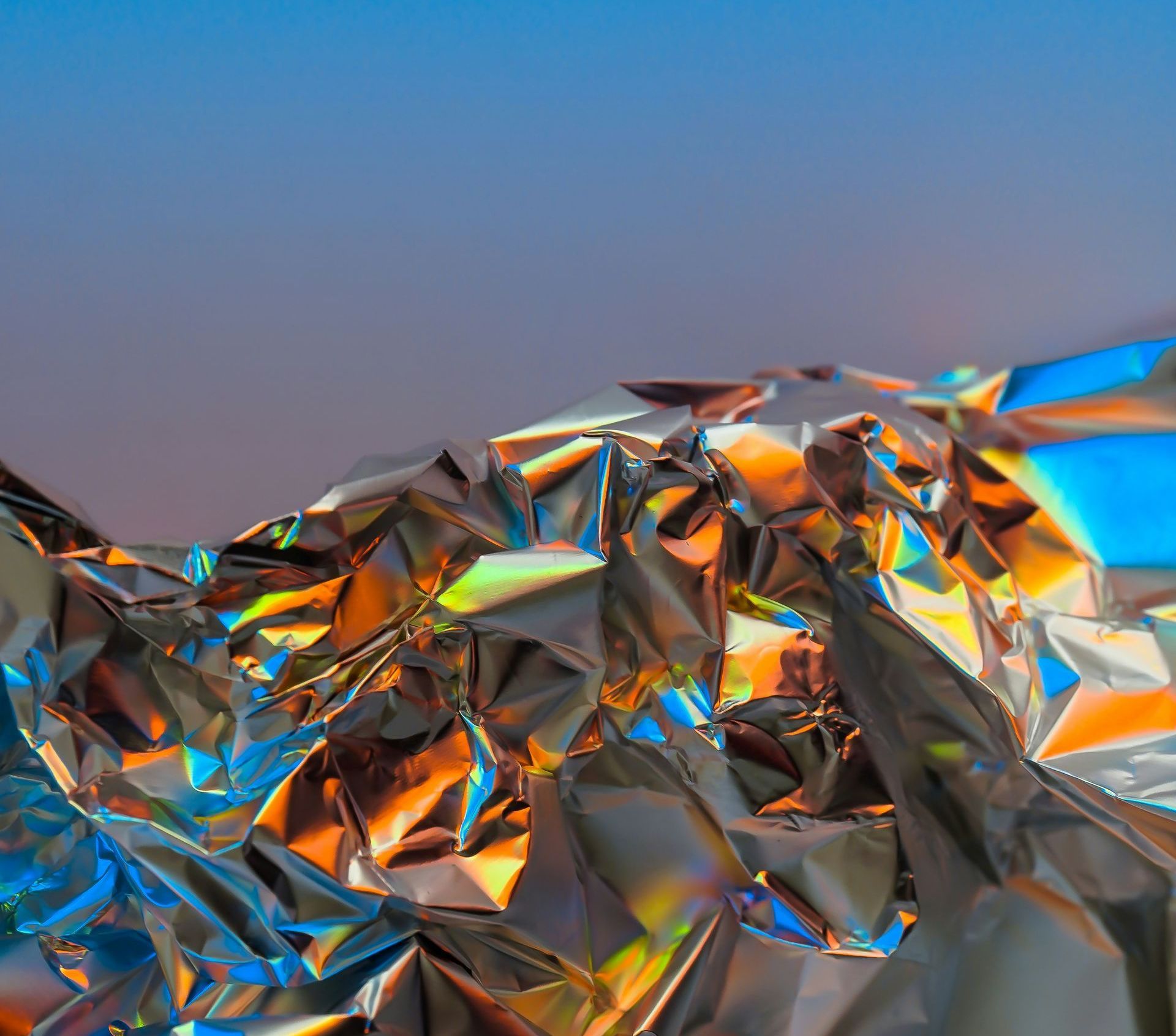 A close up of a piece of crumpled aluminum foil on a blue background.