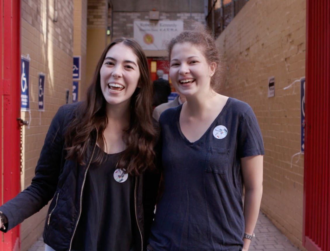 Two woman standing outside NYC voting booth smiling