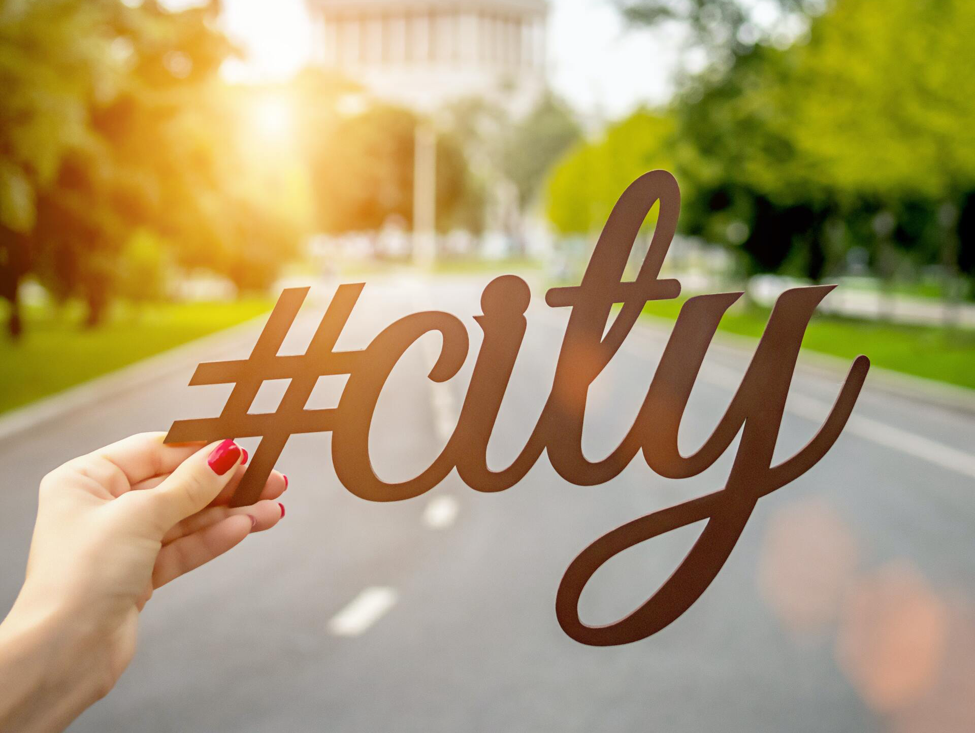 close up image of woman's hand holding a hashtag next to the word city