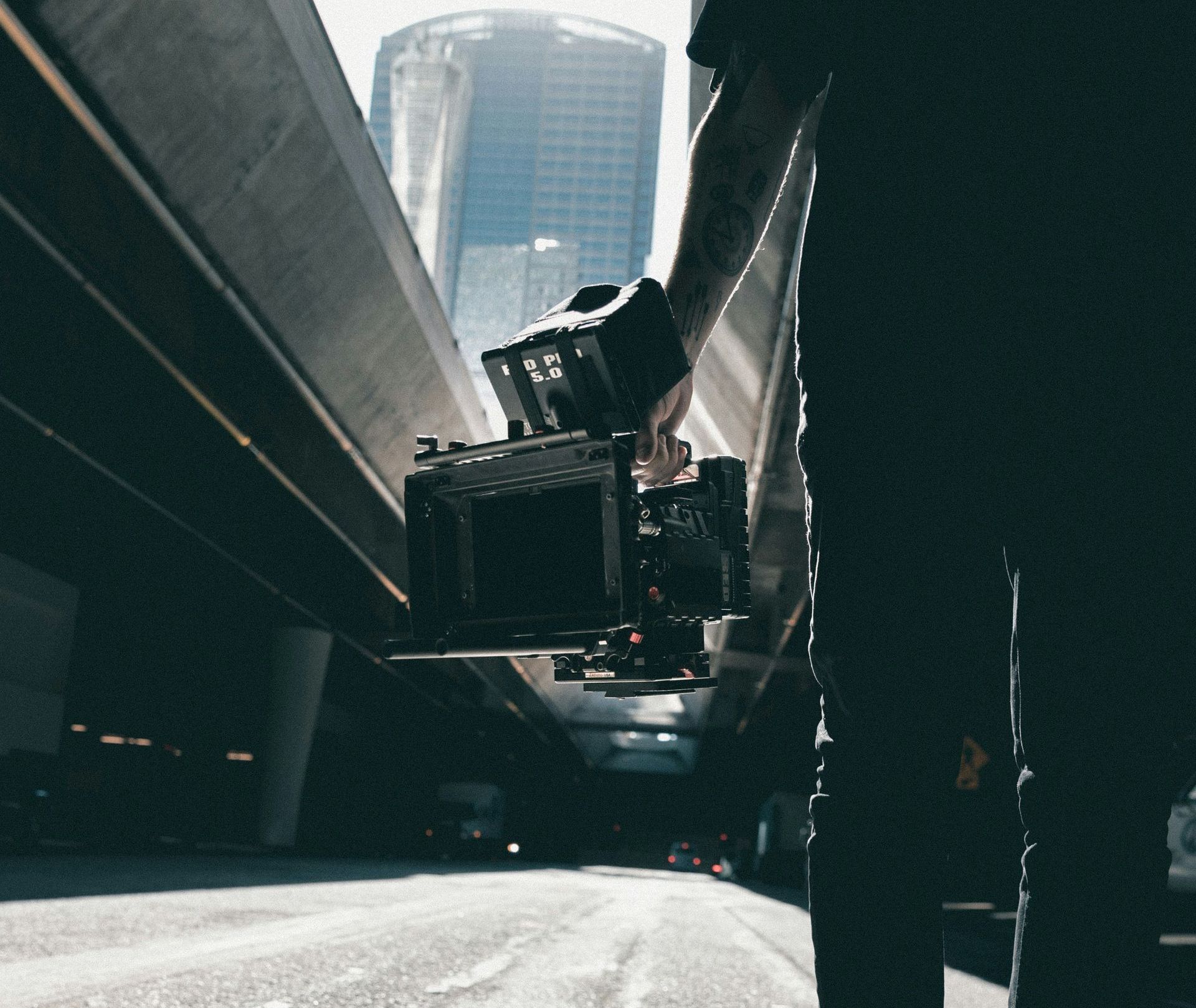 Man carrying a red cinema camera in a city Man carrying a red cinema camera in a city