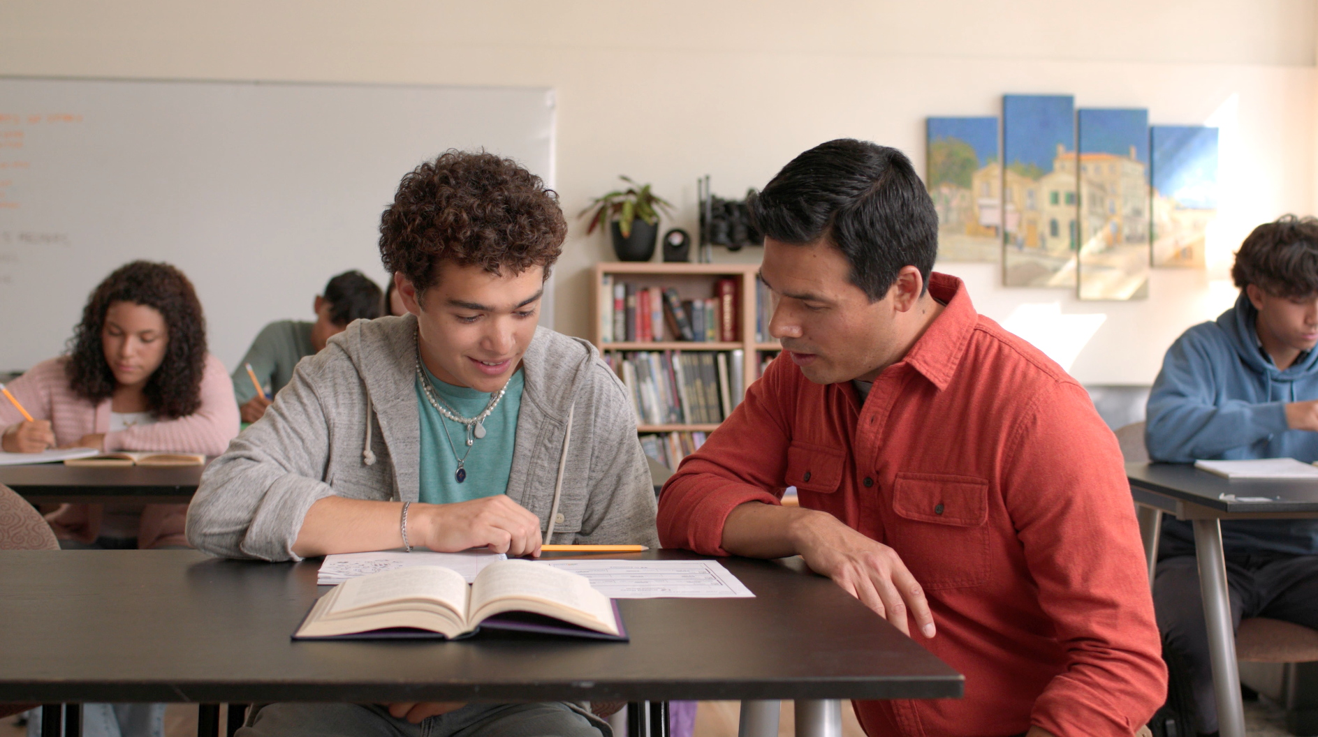 A man and a woman are sitting at a desk in front of a computer.