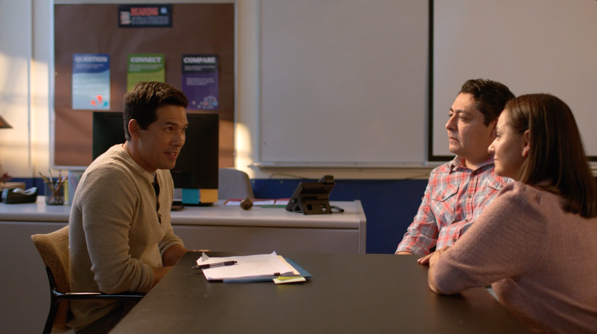 A woman is sitting at a desk with three computer monitors on it.