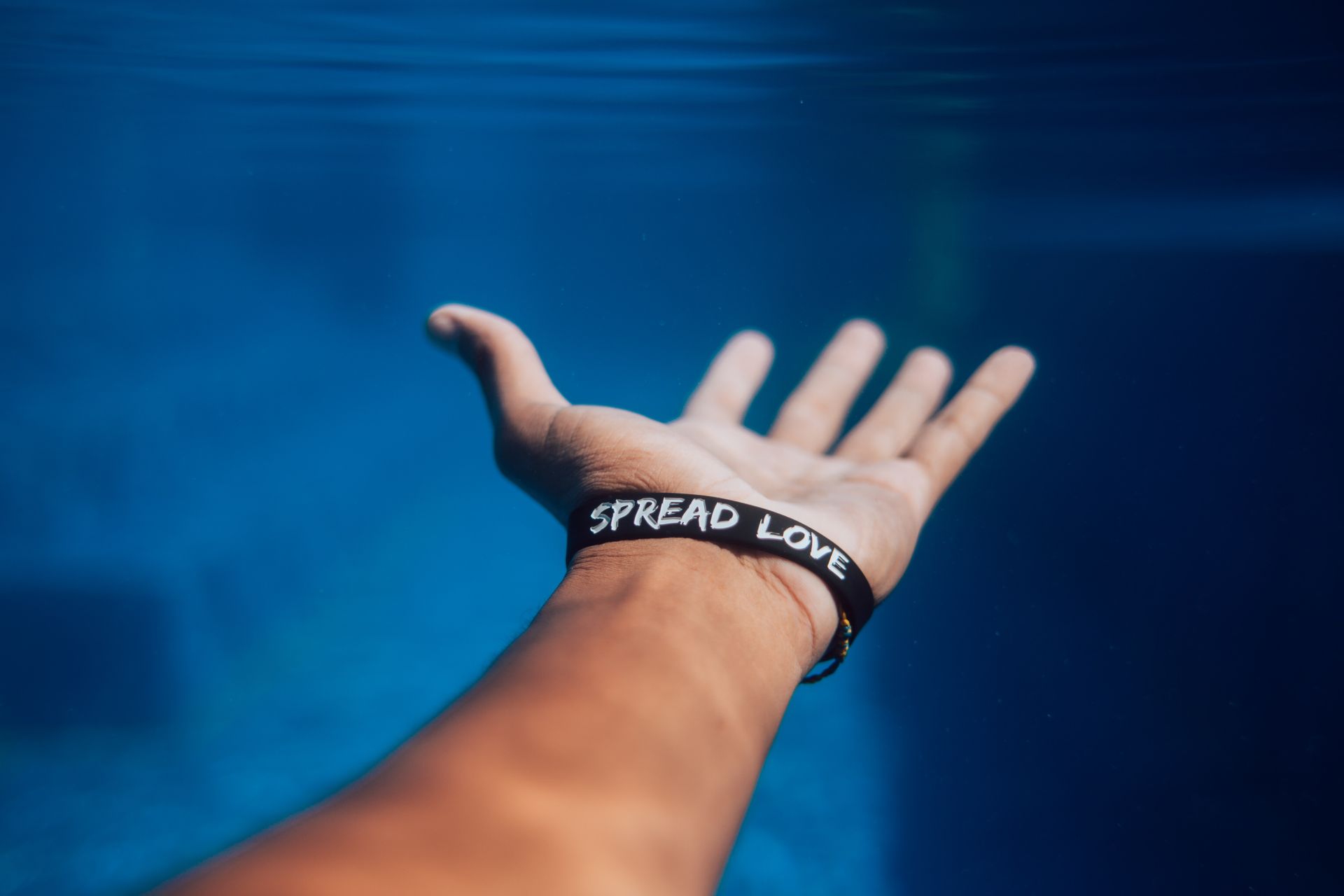 Hand reaching out with wrist band that says spread love