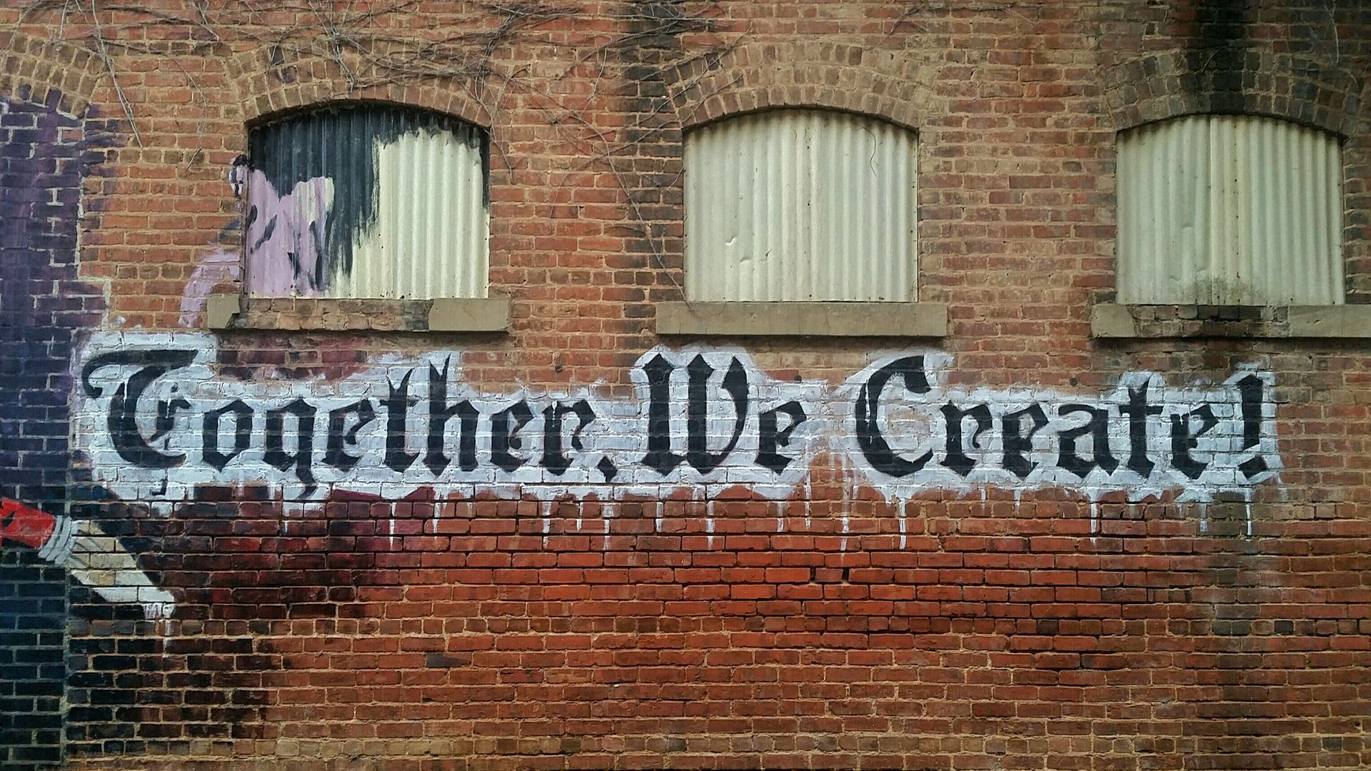 Together We Create! sign painted on old brick building wall