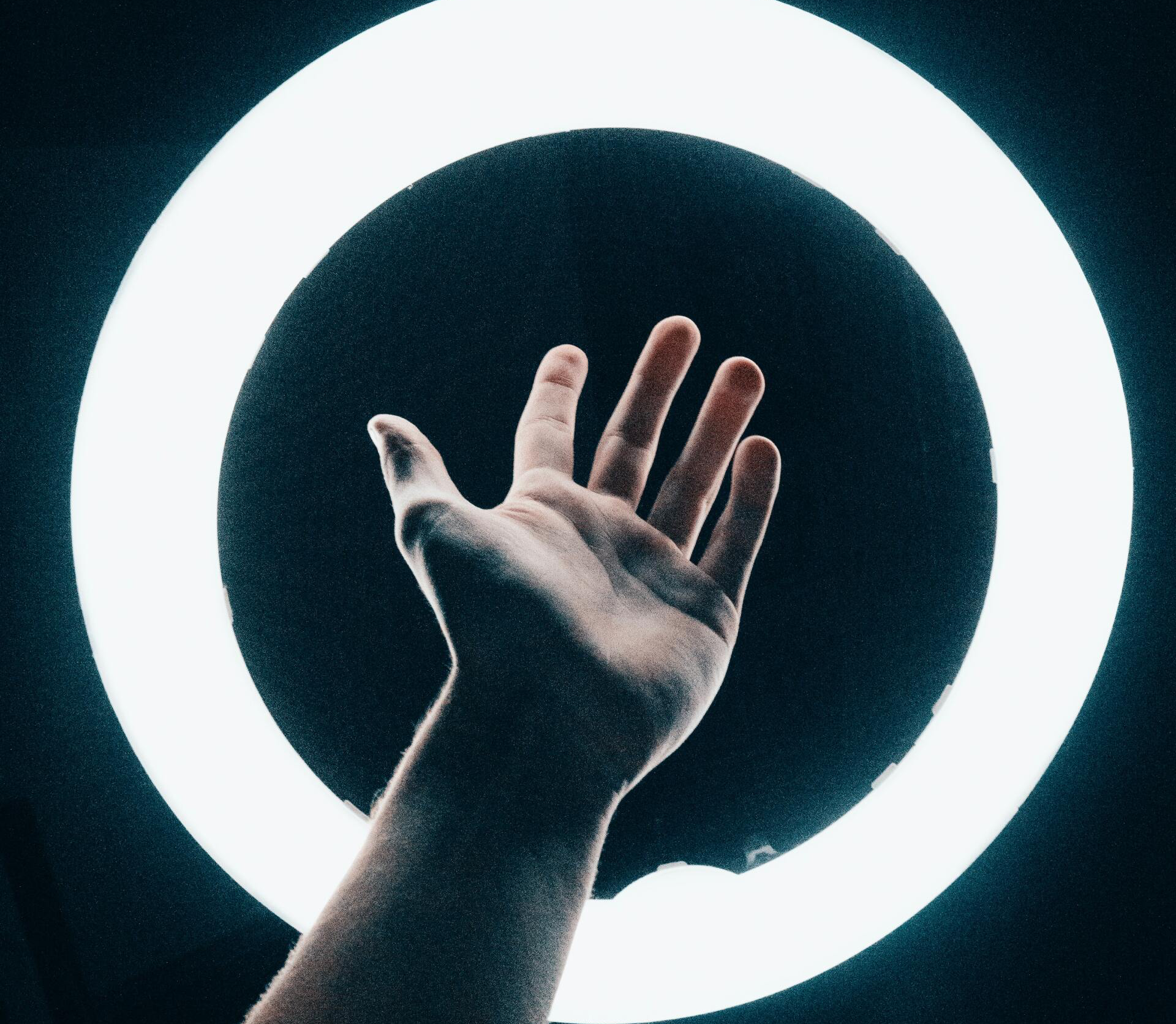 Hand reaching between a white ring light