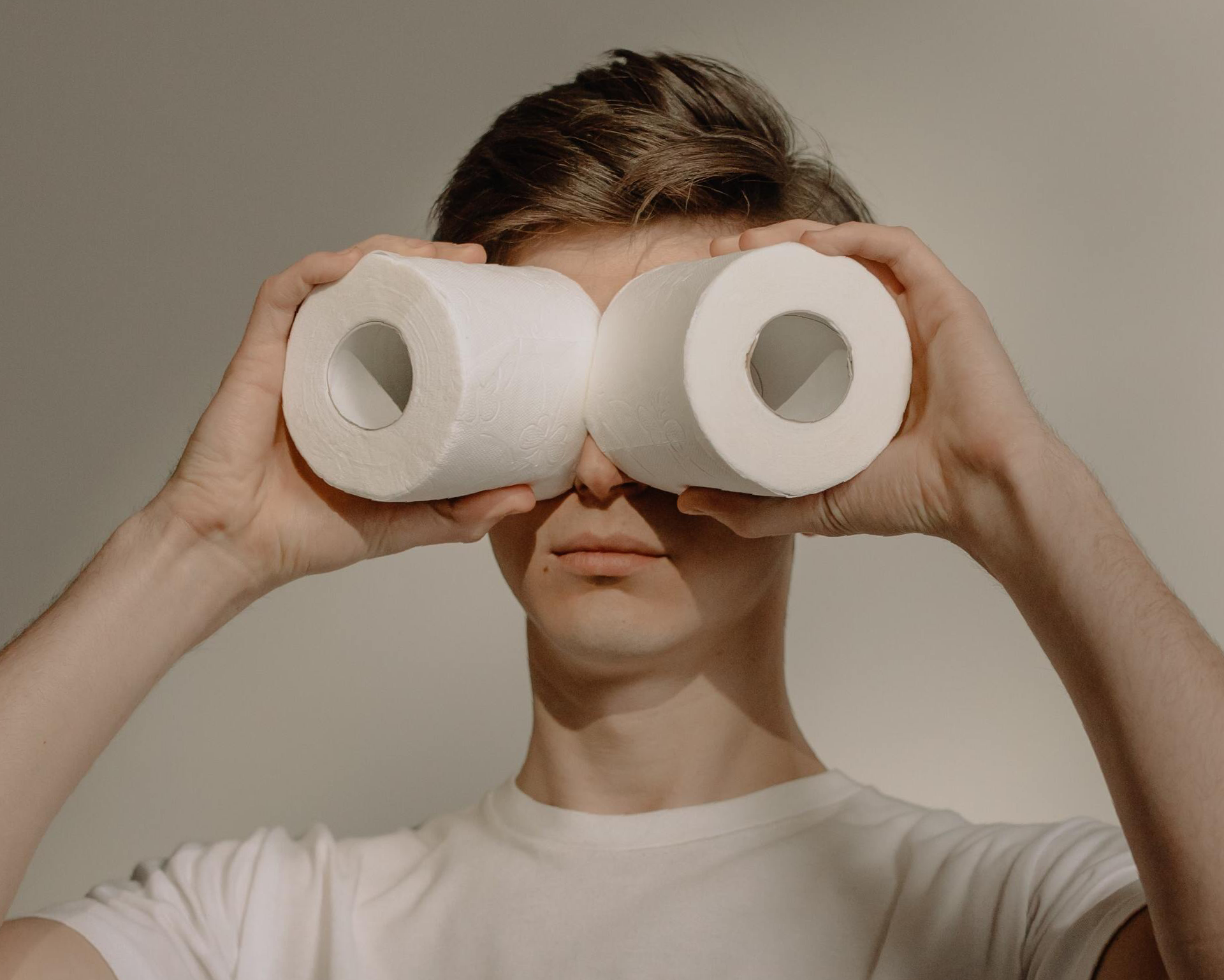 Man holding toilet paper rolls in front of his eyes