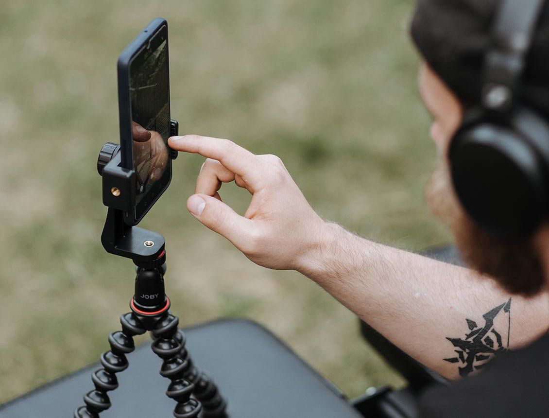Image of a man using an iPhone on a tripod wearing headphones