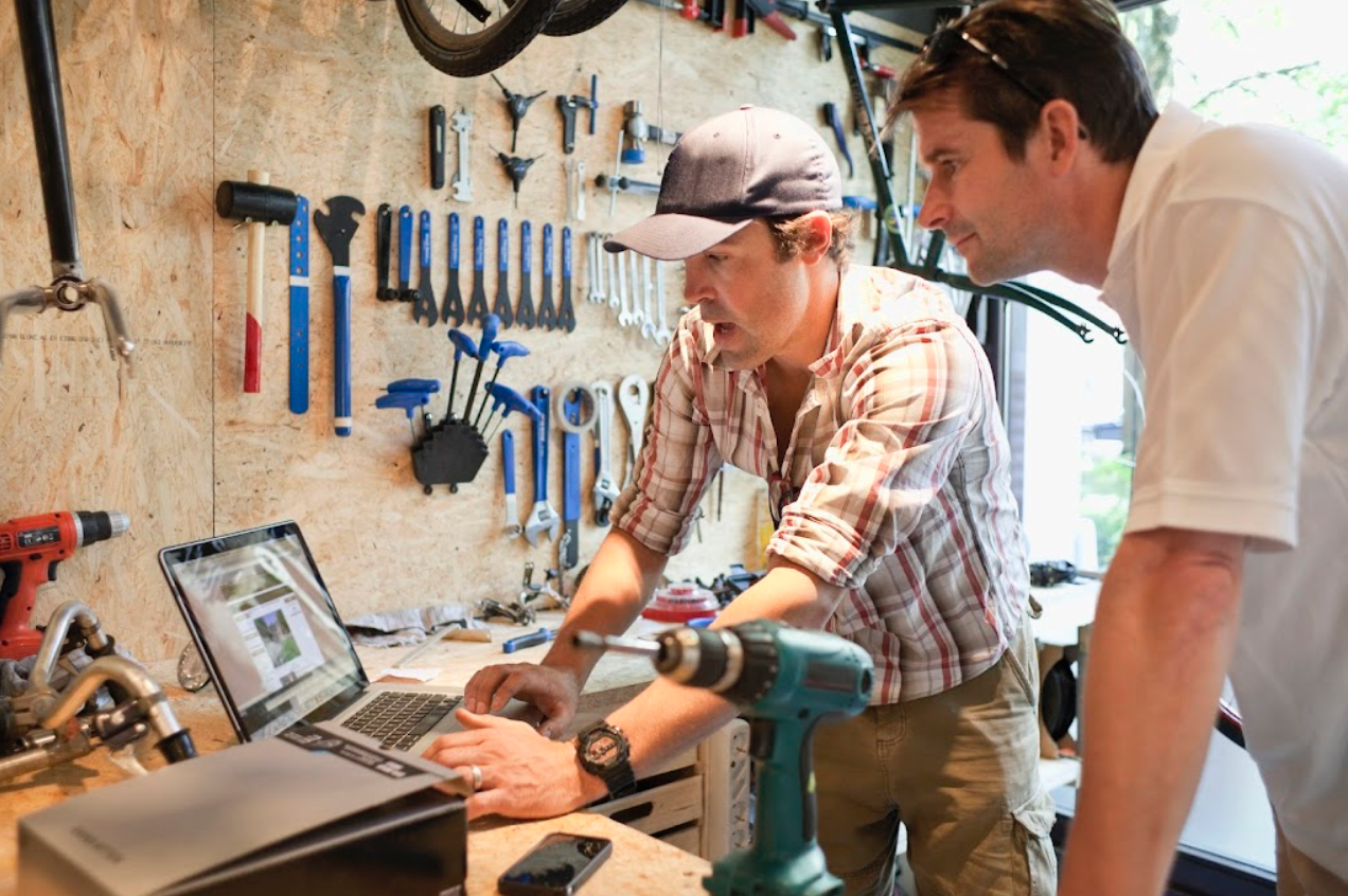 Two men looking at computer in small business bike shop