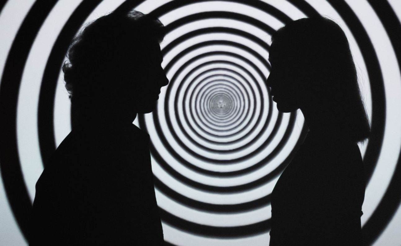 Couple facing each other in silhouette with rings of black and white behind them