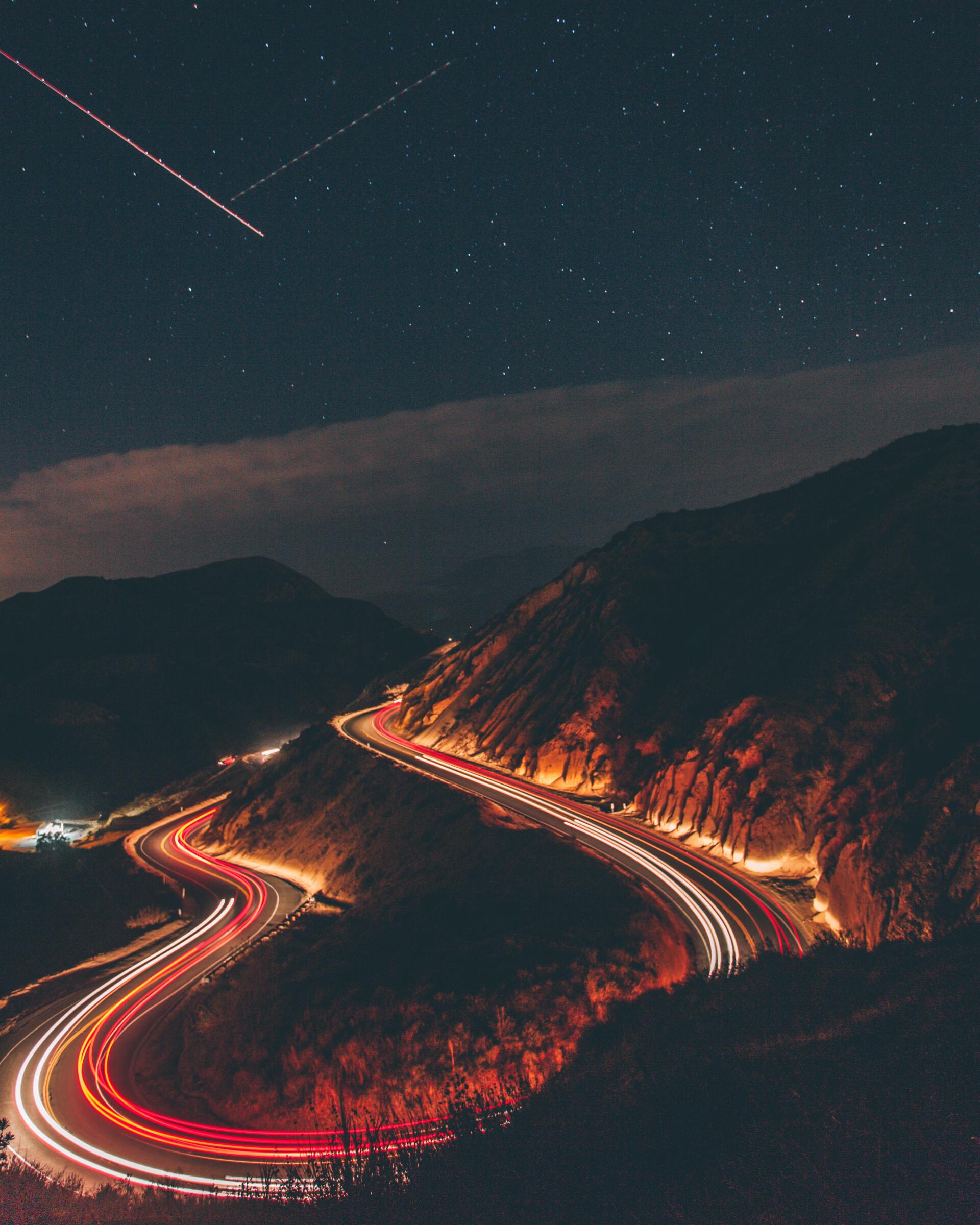 image of time lapse cars driving on mountain with shooting stars in sky