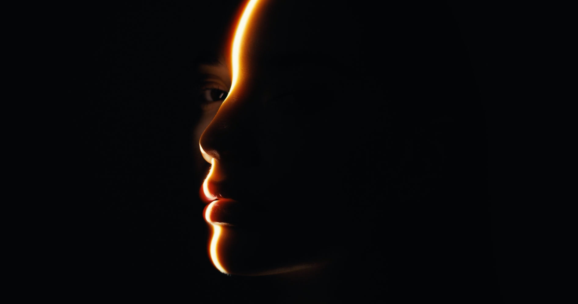 A close up of a person 's face in the dark with a light shining on it.