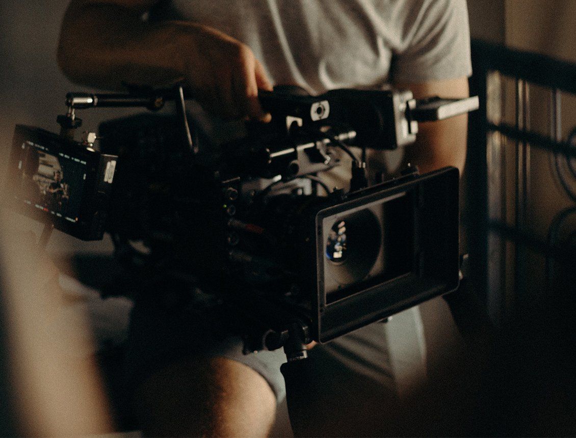 Image of a cameraman hand holding a cine style video production camera with matte box