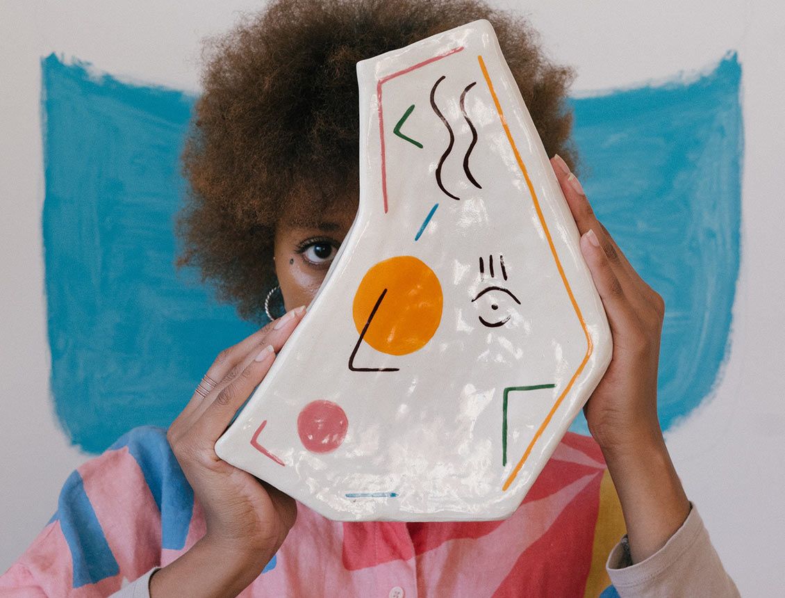 Photo of woman holding abstract art staring at camera
